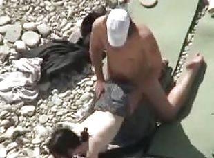 Lewd couple makes love on a nude beach in the presence of their friends