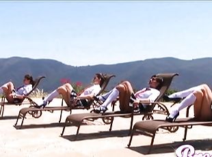 Four beautiful ladies in plaid skirts and knee high socks tan outdoors