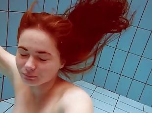 Lola, a girl with big natural tits, swims underwater.