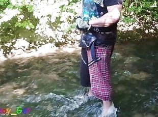 German guy stands in a creek, pisses and jerks off his hard cock