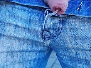 Pissing outdoors wearing jeans